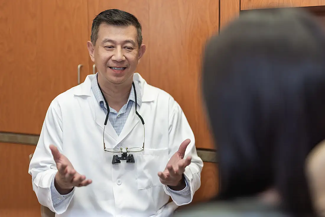 Dr. Tom Jou talking with a patient in the dental chair