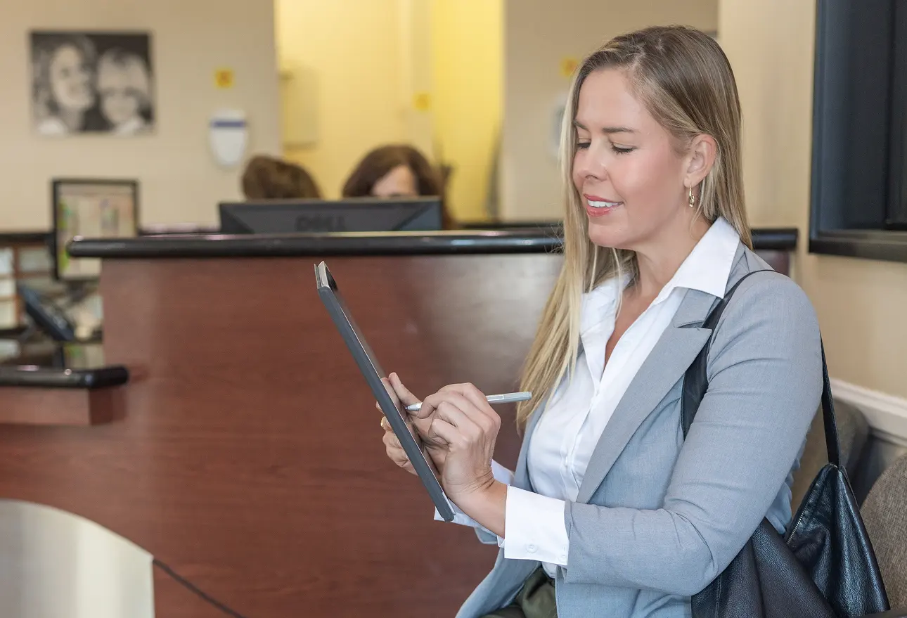 Woman completing dental forms in a dental office waiting room